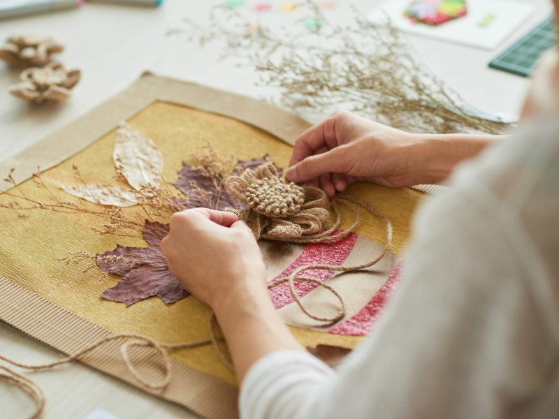 Close-up shot of talented woman sitting at desk and giving final touches on creative decor item